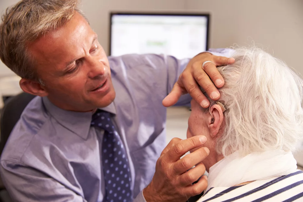 Audiologist performing a hearing aid fitting on elderly woman