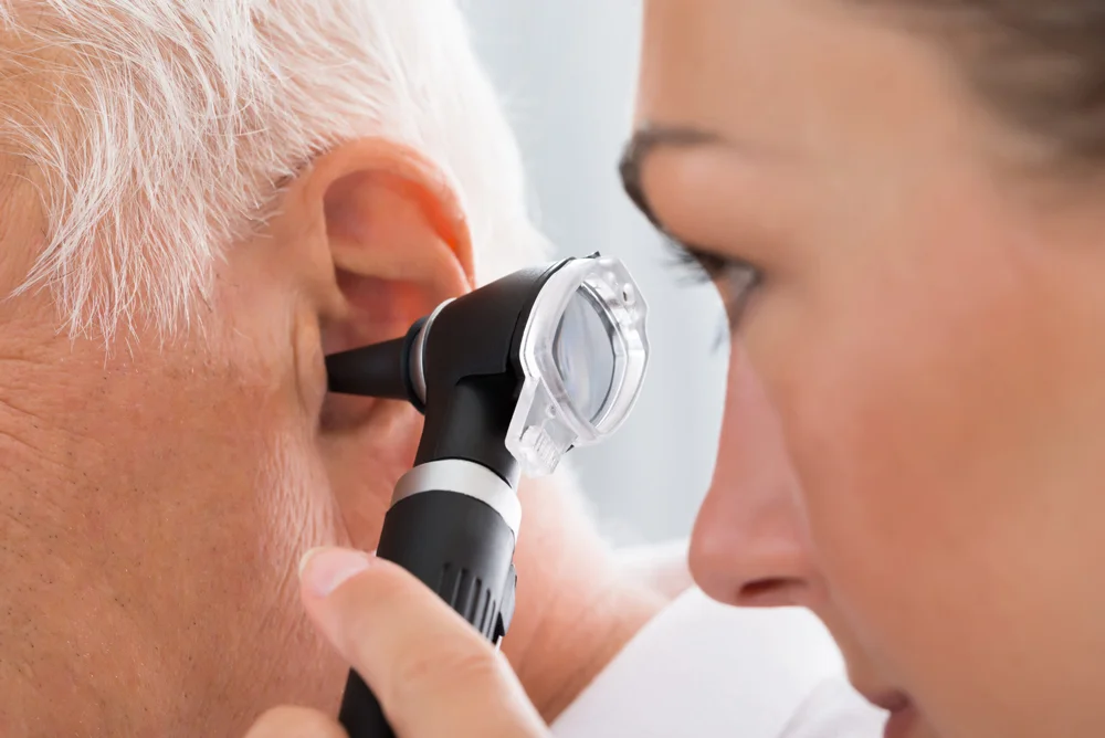 Female hearing care professional examining elderly patient's ear