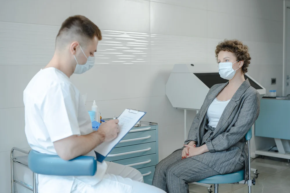 Young male medical professional talking to a female patient and taking notes