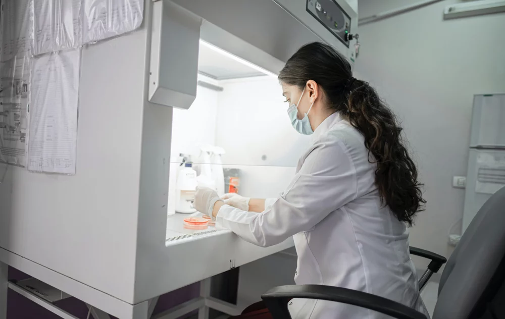 Female pharmacist wearing a mask sitting in front of desk working on probes