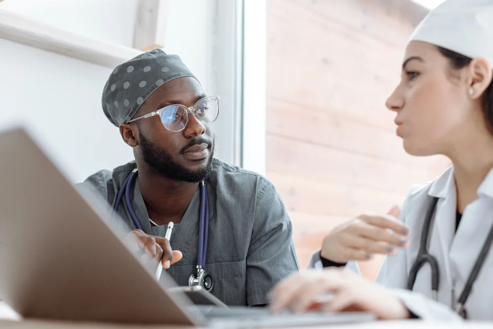 Two healthcare professionals sitting in front of a laptop and having a discussion