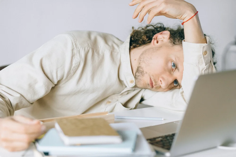 Tired-looking employee at his desk leaning on his arm