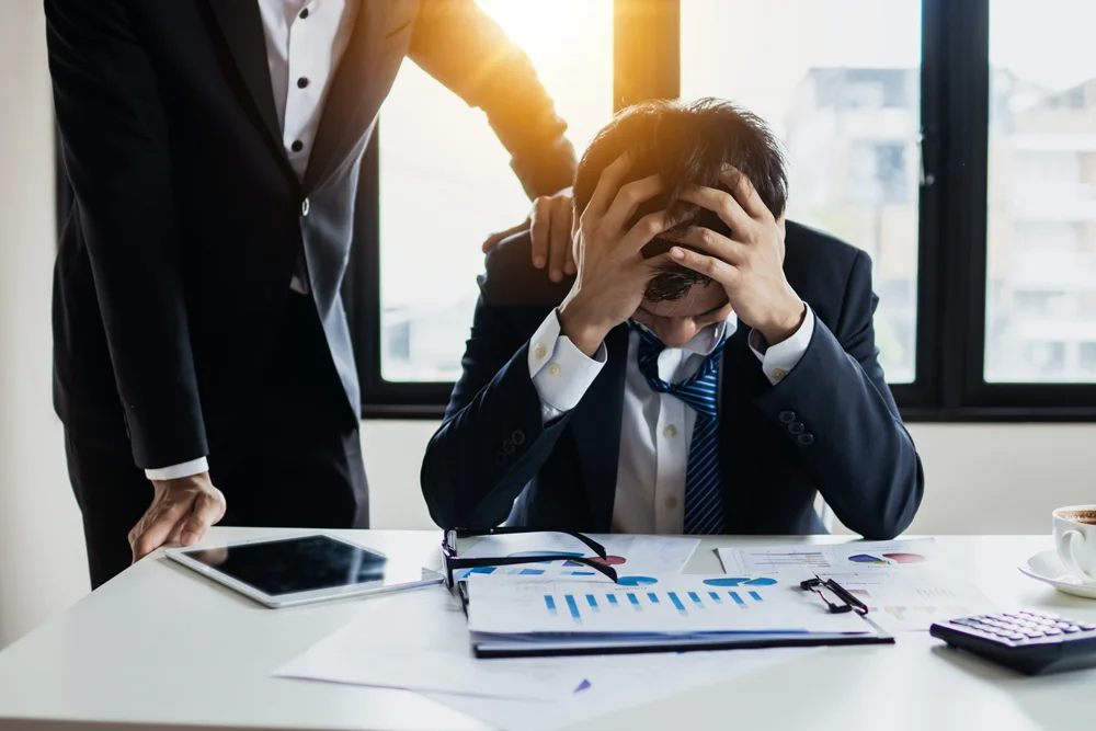 Employee in distress being comforted by a colleague