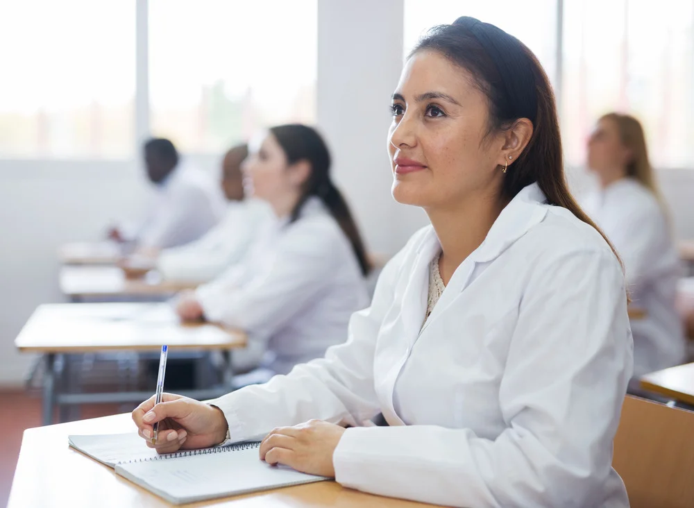 Smiling woman taking part in healthcare course taking notes, looking ahead